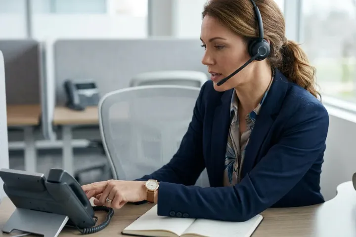 A consultant at her desk taking a client call with a headset